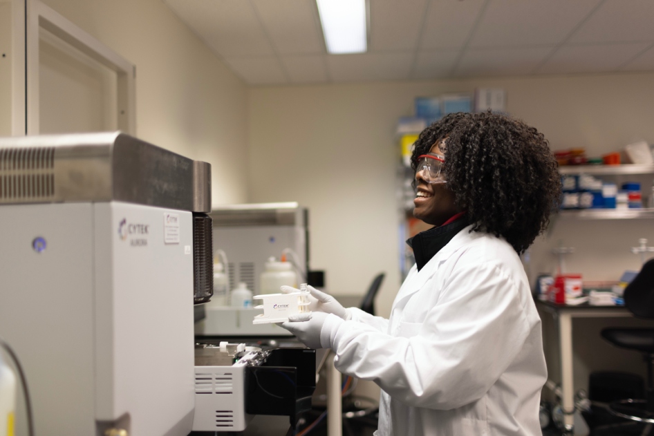 Scientist operating a flow cytometry instrument.