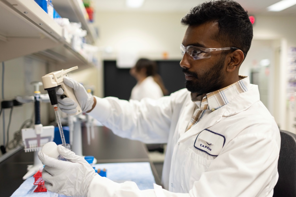 Scientist pipetting samples at the bench.