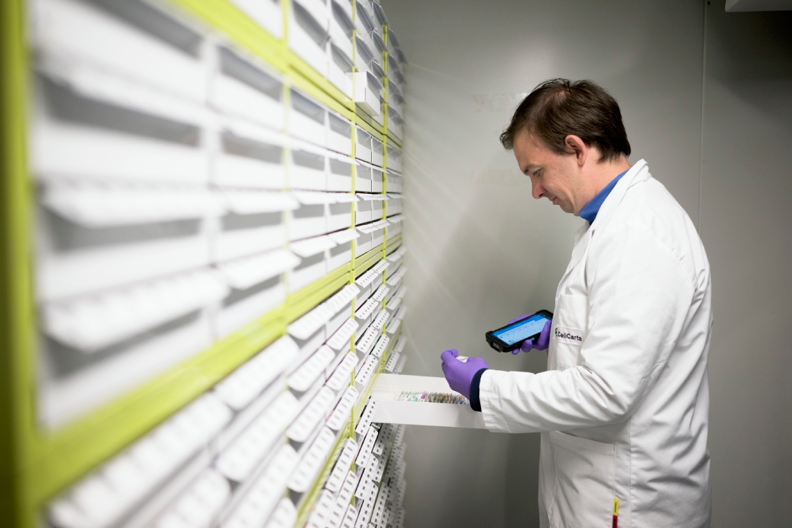 Scientist retrieving samples from laboratory storage racks.