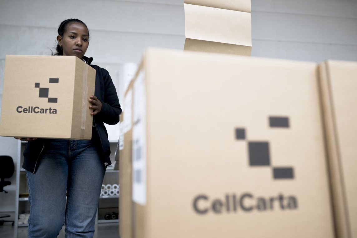 Worker carrying a CellCarta sample shipping box.