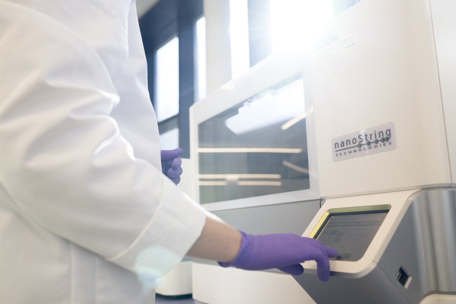 Scientist operating NanoString nCounter platform for direct gene expression counting without amplification