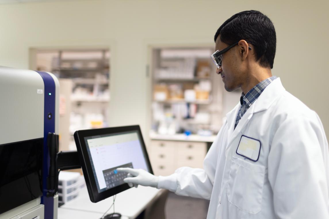 Scientist adjusting settings on a benchtop flow cytometry instrument touchscreen.