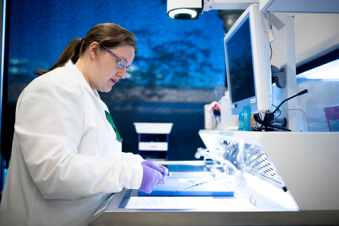 Scientist handling samples at an open workbench.