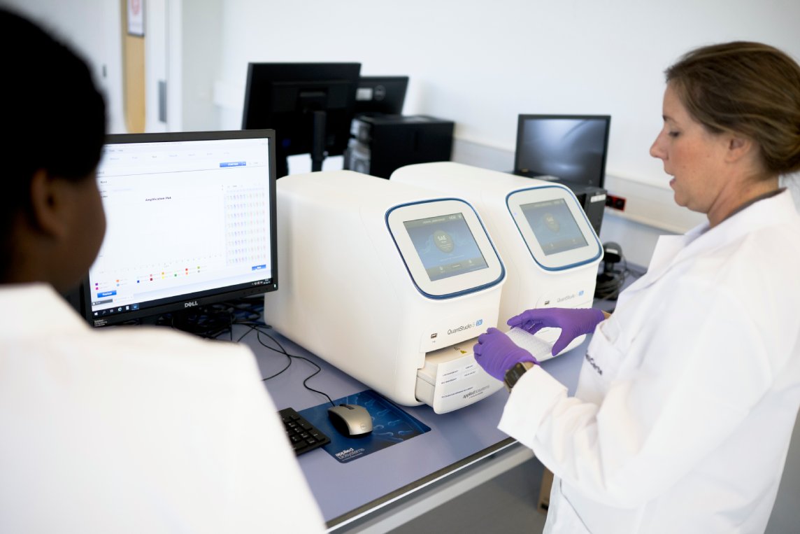 Two scientists operating a dPCR instrument at a workstation.