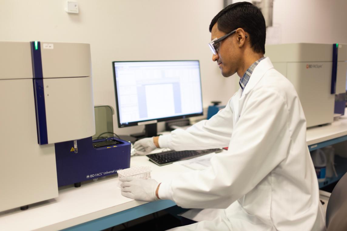 Scientist operating a flow cytometry instrument.
