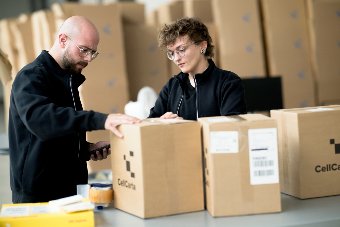 Team packing sample kits into a CellCarta shipping box.