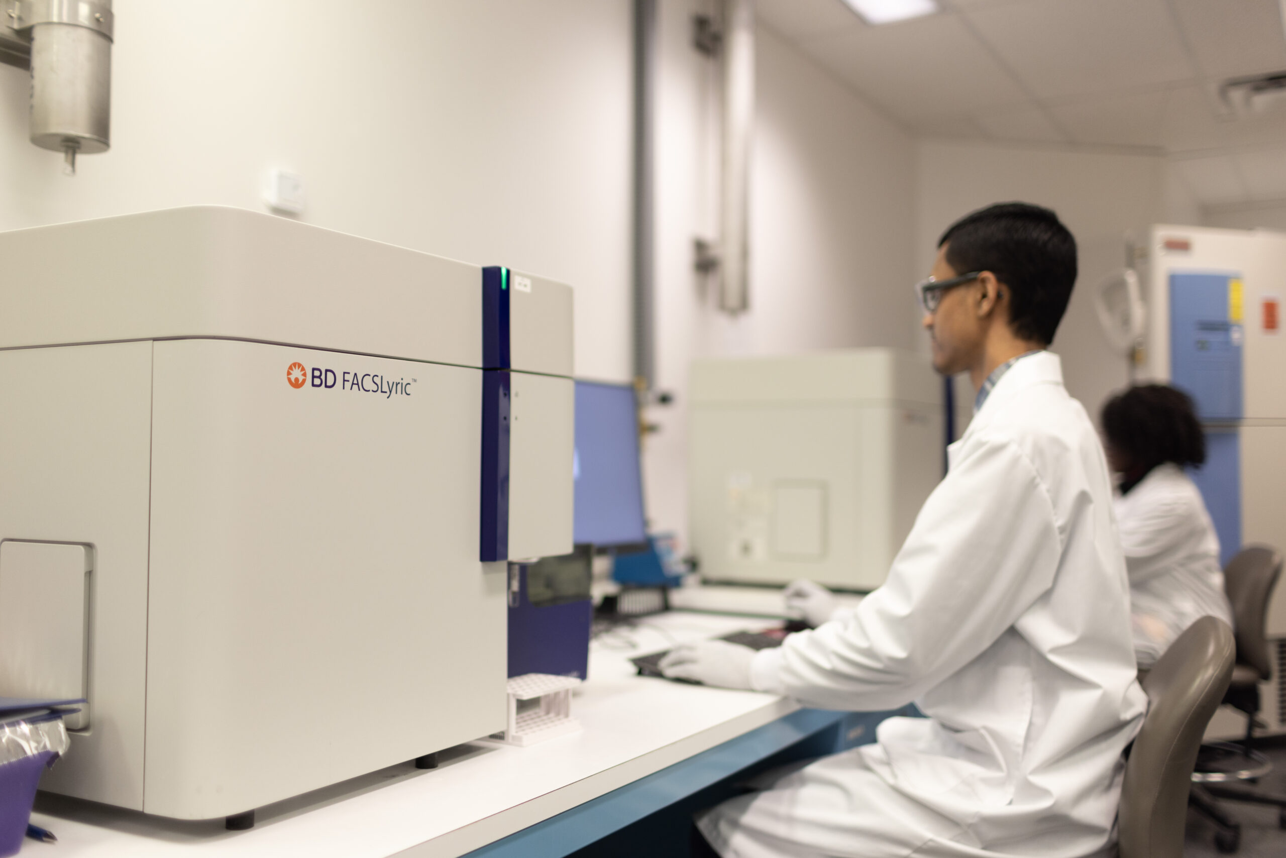 Two scientists operating BD FACSLyric on benchtop.