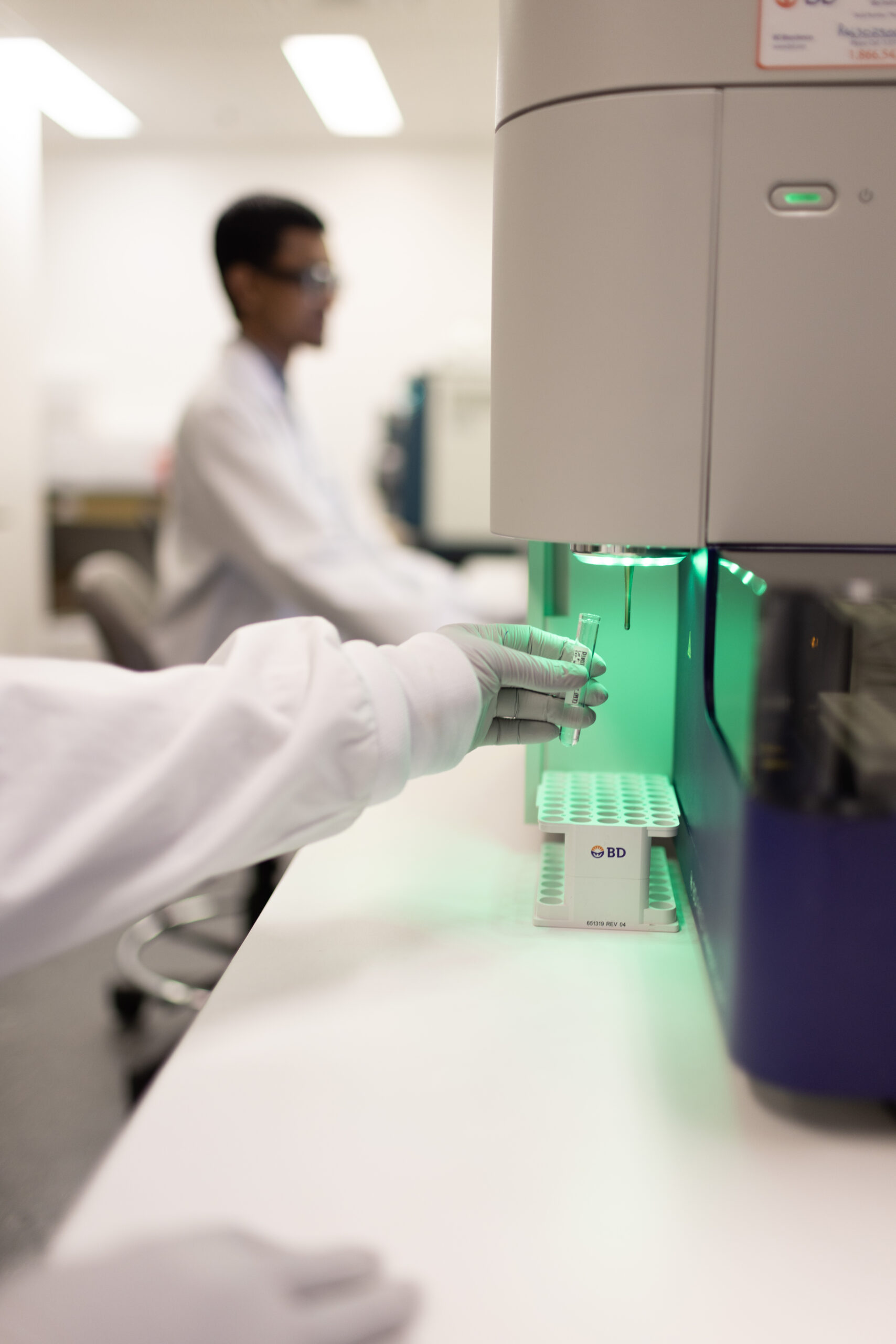 Scientist loading samples into a benchtop flow cytometry instrument.