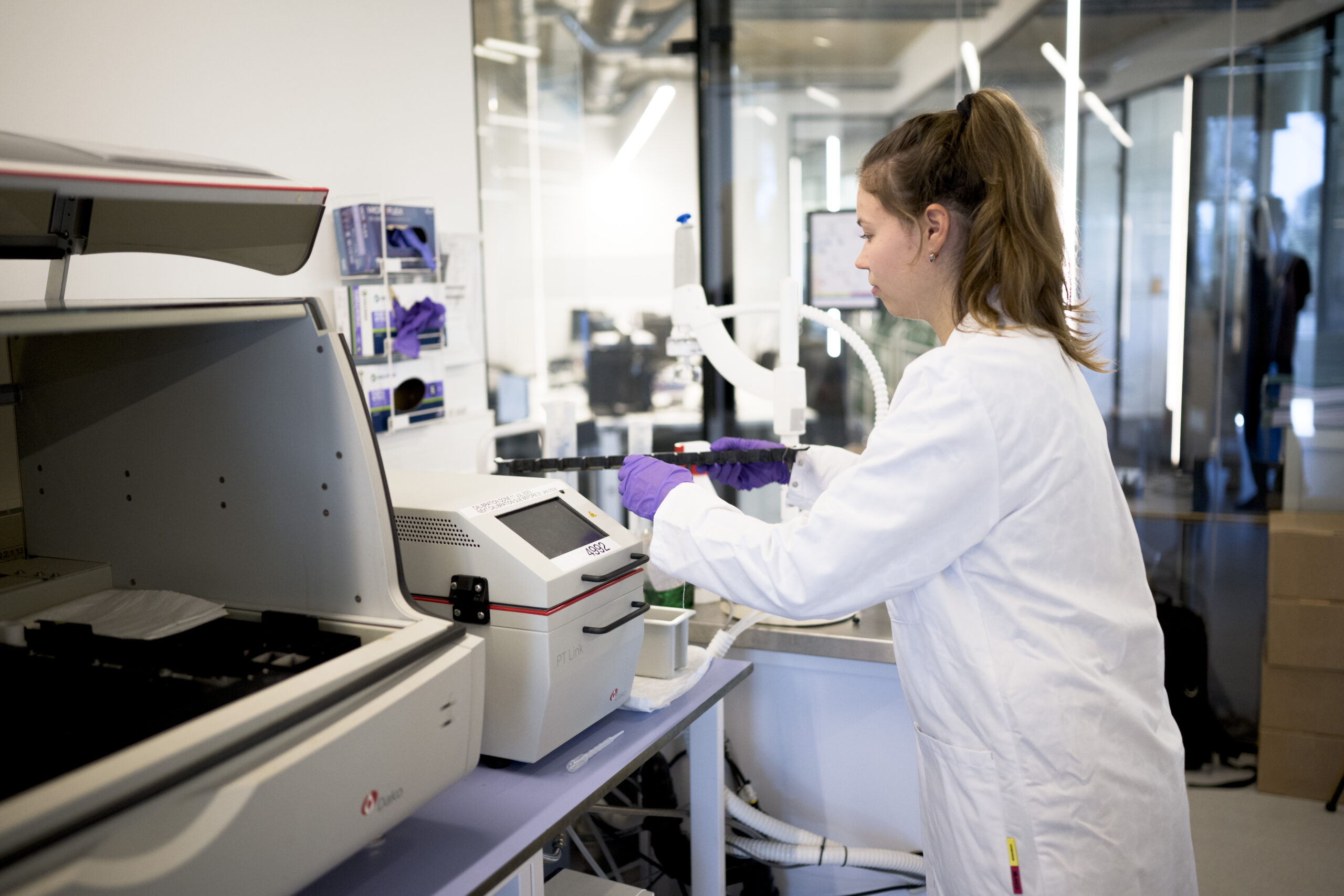 Scientist operating a benchtop instrument at a data workstation.