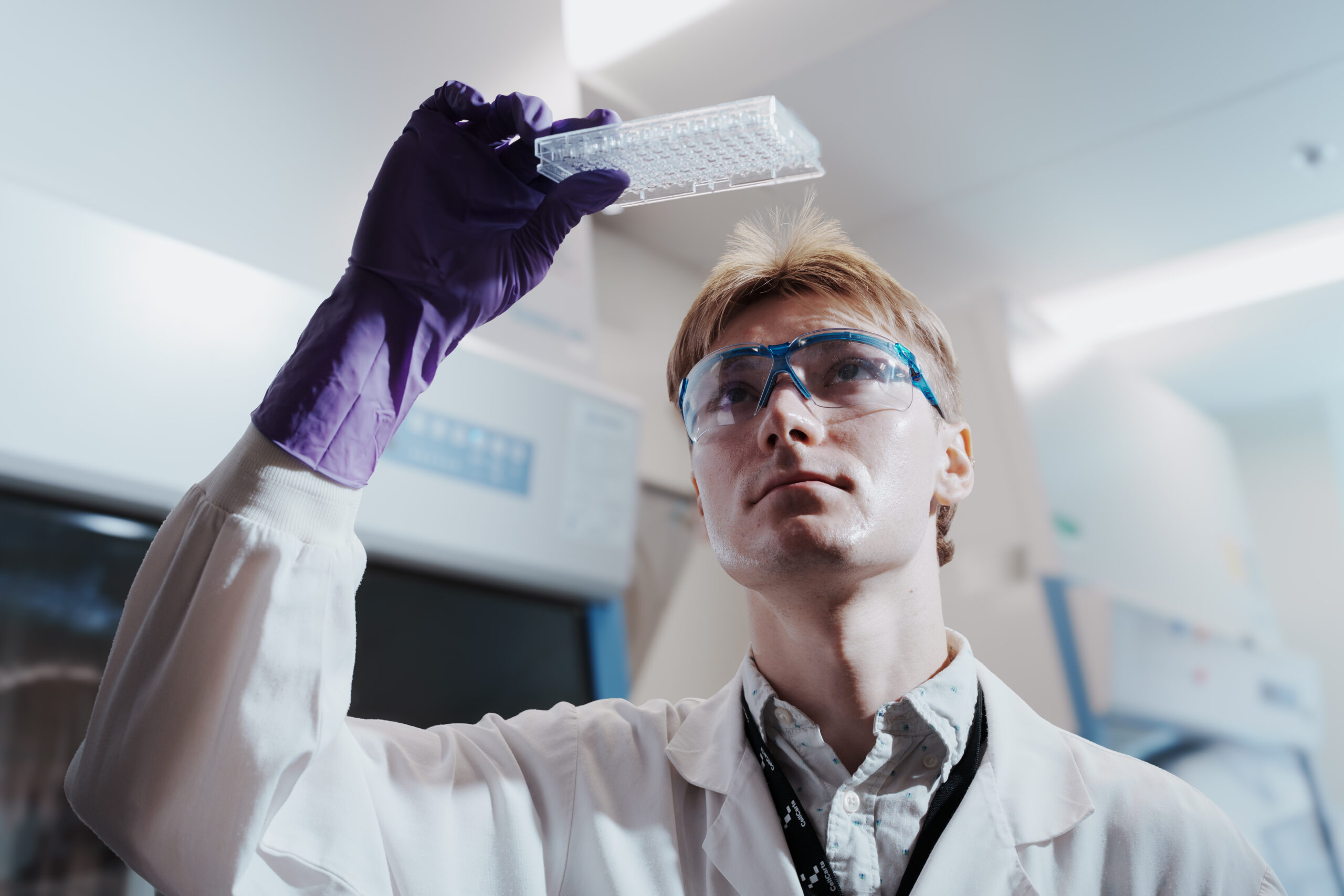 Scientist inspecting a sample vial held up to the light.