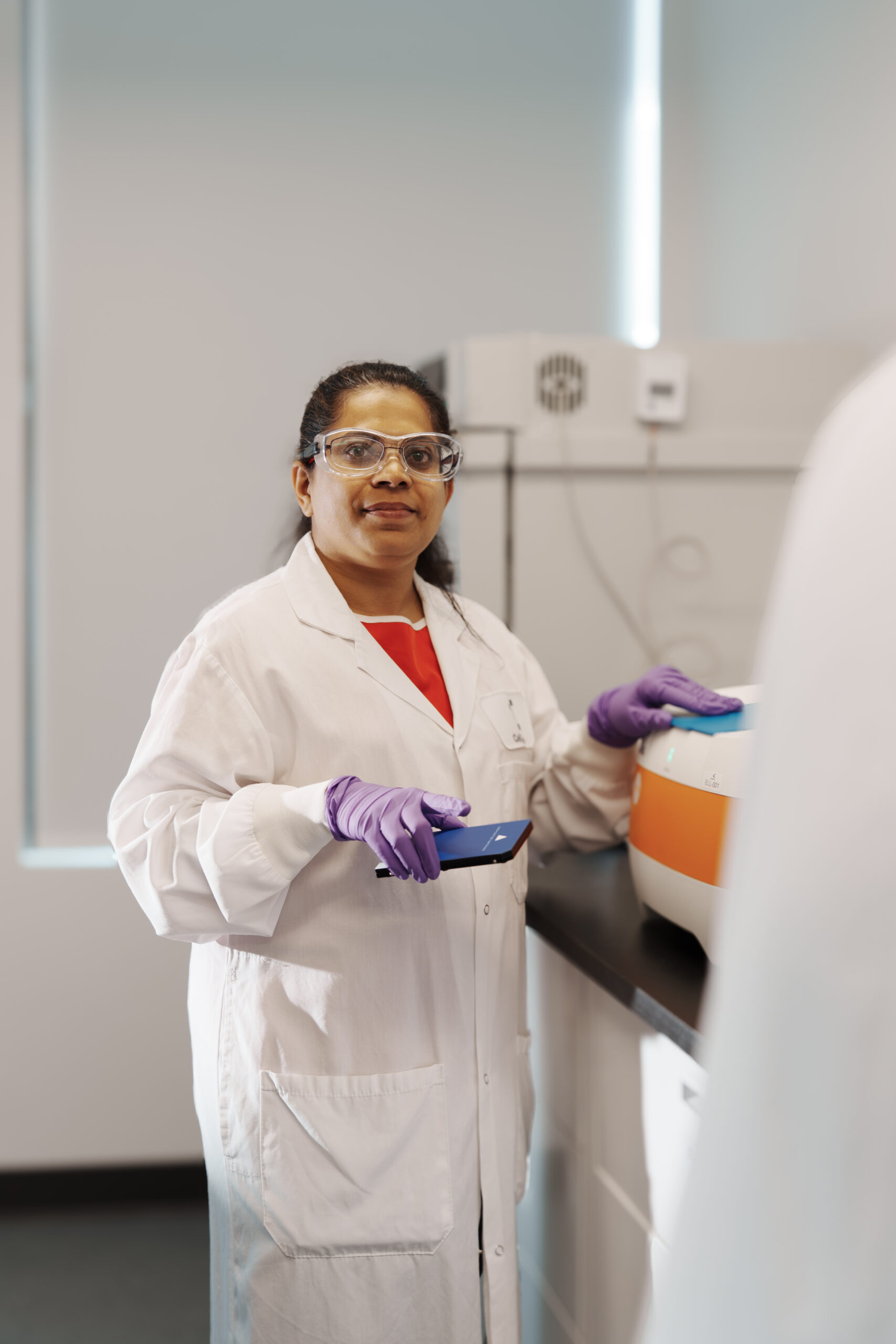 Scientist holding a sample container in the laboratory for Ella.